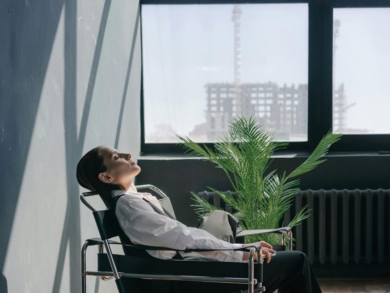 Frau sitzt pausierend in einem Bürosessel